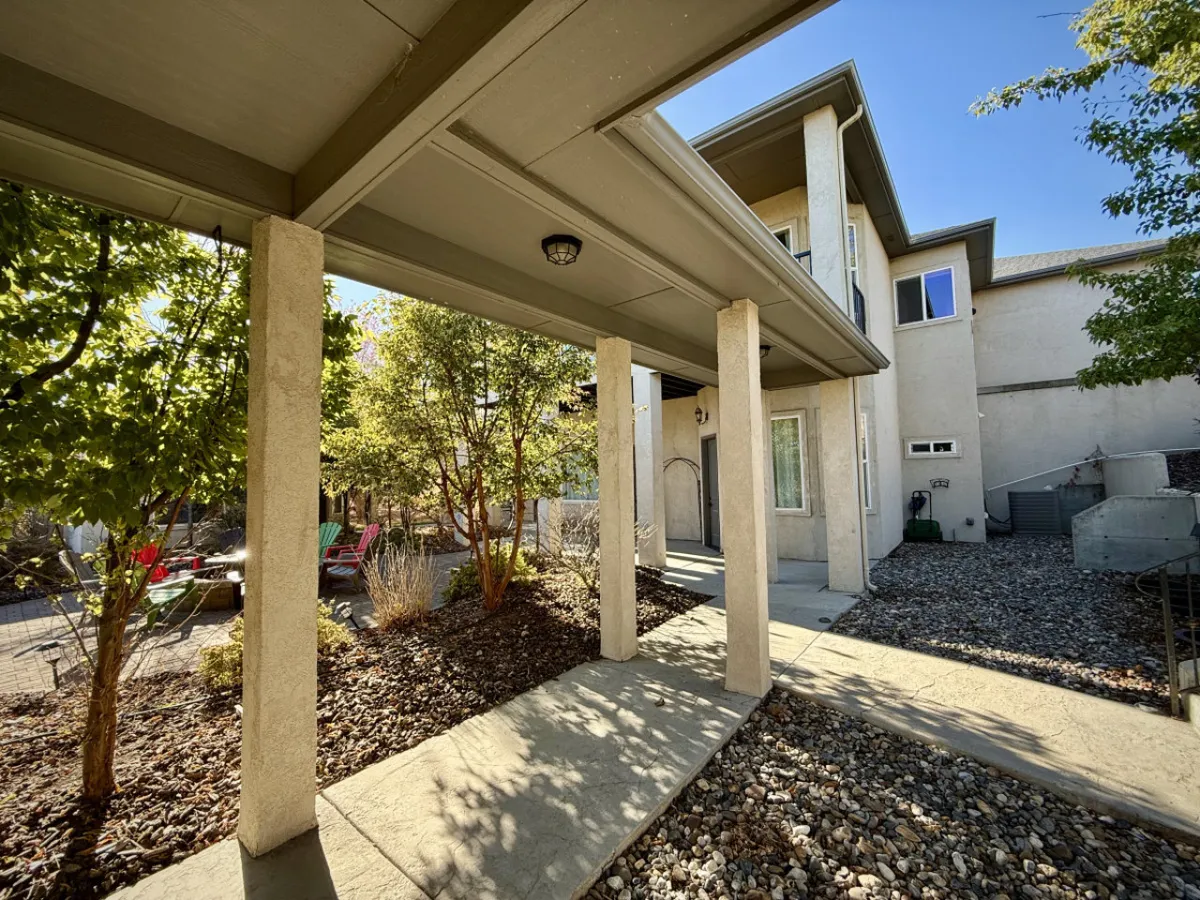 An inviting view of a covered porch and landscaped yard at the entrance to the property. The setting hints at relaxation and social gatherings, with ample space for families and pets to play or unwind together.