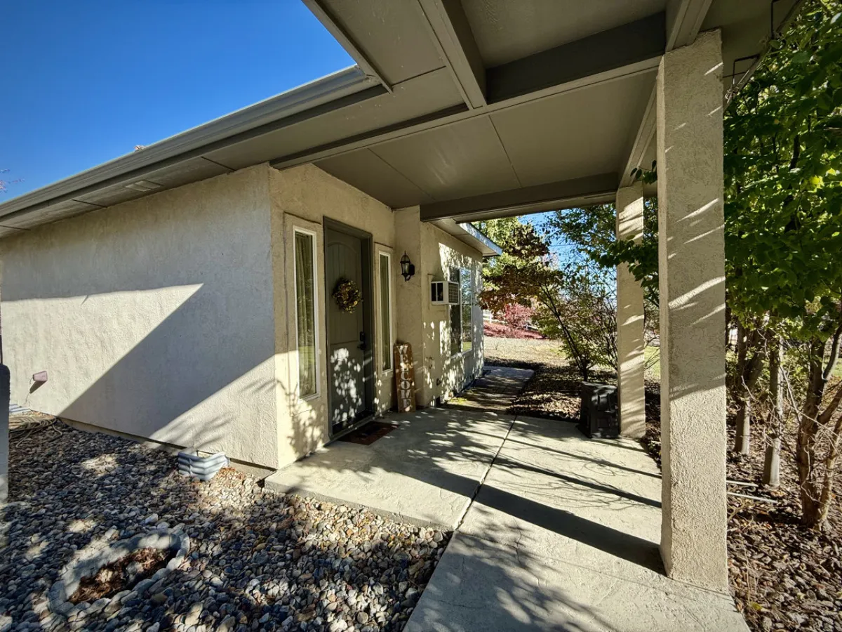 An inviting front entrance with a decorative wreath, landscaped pathway, and lush greenery. The exterior exudes warmth, privacy, and the promise of a tranquil retreat.