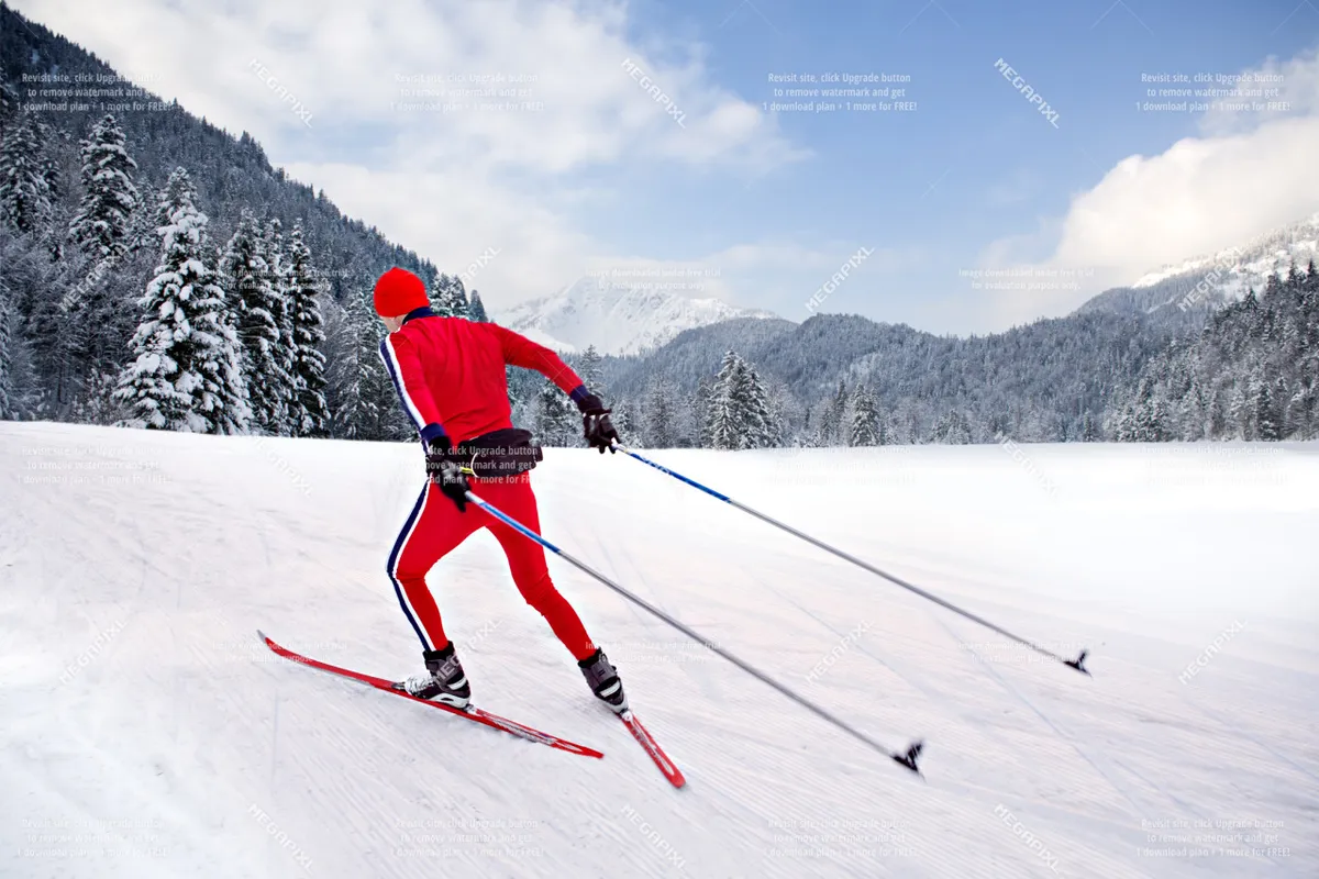 An energetic outdoor scene featuring a skier in a red outfit gliding across a snow-covered landscape dotted with evergreen trees. The image captures the thrill of winter sports amid a stunning natural setting.