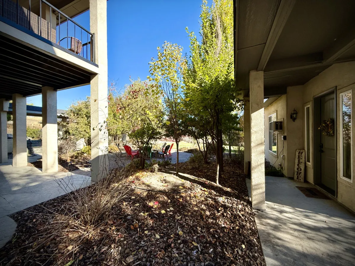 The image captures a cozy patio area with red chairs, a garden pathway, and the welcoming front door. It suggests a space for intimate conversations, sharing stories, and enjoying the outdoors as a group, especially in the evening or after adventures.